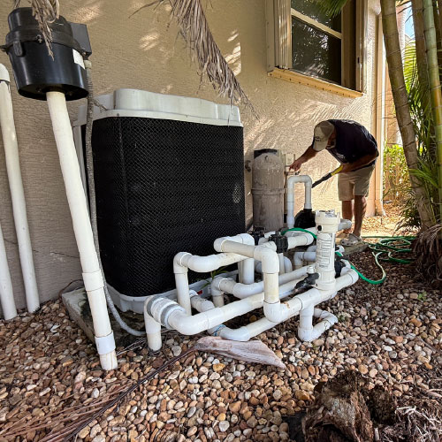 Pool technician inspecting pump and filter equipment near Port Charlotte home