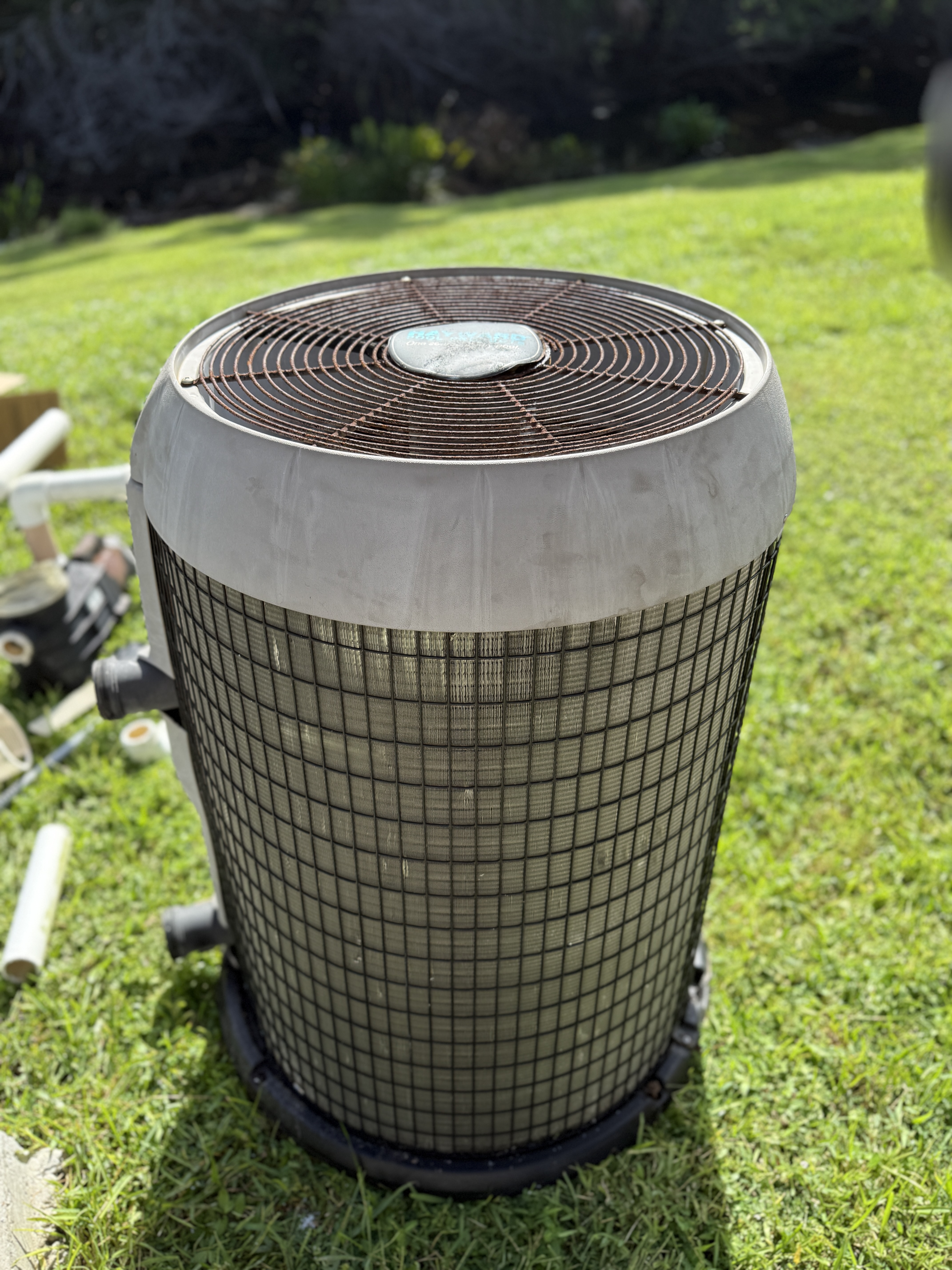 Old electric pool heater with visible rust and corrosion sitting on a lawn in Charlotte County, Florida — an example of a unit that needs replacement.