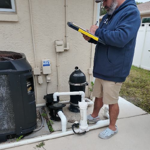 Pool technician performing equipment inspection during weekly pool service in Punta Gorda including pump and filtration system evaluation.
